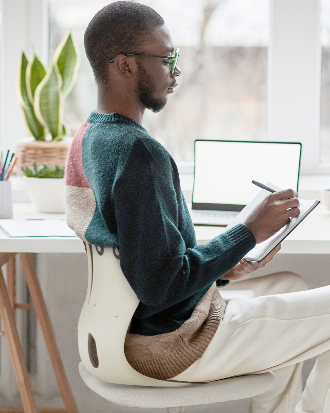 デスクチェアの上にCurble Chair Grandを置いて座り、デスクで作業する様子